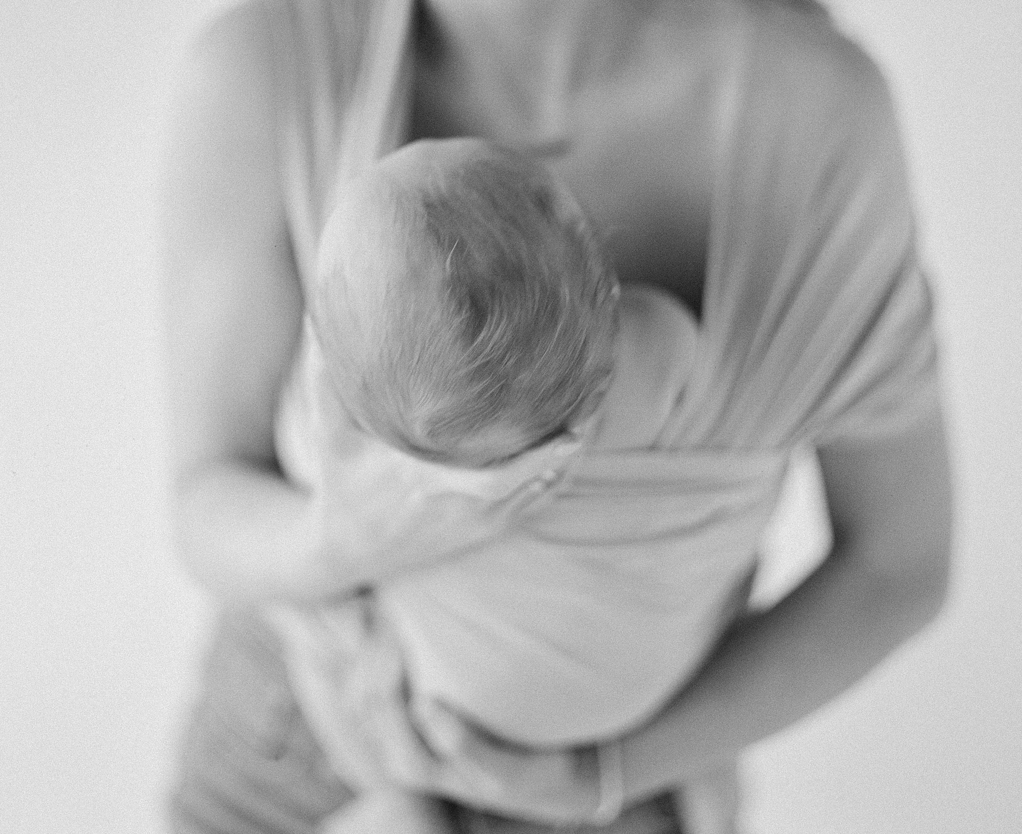 Black and white film photo of a woman holding her baby in a wrap by Hope & Plum.